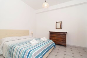 A bedroom with a bed, a wooden dresser, a mirror, and a lamp. - Limoneto - Combo by Espresso Rentals (Massa Lubrense)