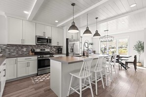 A modern kitchen with white cabinetry, stainless steel appliances, and pendant lighting. - Gone Ski Inn! Cozy Townhome Perfect for Families (Kamas)