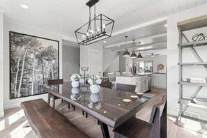 A modern kitchen with a central island, pendant lighting, and a large dining table with benches. - Gone Ski Inn! Cozy Townhome Perfect for Families (Kamas)