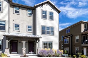 A multi-story residential building with a covered front porch and a stone pillar. - Gone Ski Inn! Cozy Townhome Perfect for Families (Kamas)