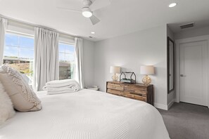 A bedroom with a large bed, a dresser, two lamps, and a ceiling fan. - Gone Ski Inn! Cozy Townhome Perfect for Families (Kamas)