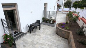 A patio area with a table and chairs, a small garden with plants, and a white wall. - Nonna Mary - Combo by Espresso Rentals (Sant'Agata Sui Due Golfi)