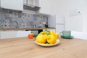 A kitchen with a wooden table, a plate of lemons, and two cups. - Nonna Mary - Combo by Espresso Rentals (Sant'Agata Sui Due Golfi)