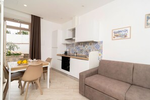 A modern apartment with a dining area, kitchenette, and a living room with a sofa. - Nonna Mary - Combo by Espresso Rentals (Sant'Agata Sui Due Golfi)
