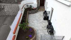 A courtyard with a seating area, a small garden, and a stone wall. - Nonna Mary - Combo by Espresso Rentals (Sant'Agata Sui Due Golfi)