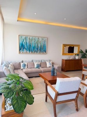 A modern living room with a sectional sofa, a coffee table, and a large abstract painting.