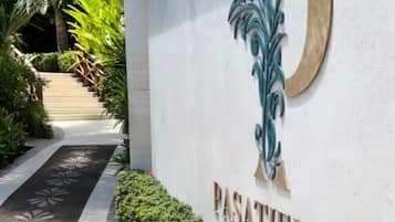 Señal para 'PASATIMPO' con un logotipo estilizado de la letra 'P', una escalera y un camino bordeado de follaje.