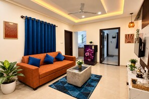 A modern living room with a sofa, coffee table, and a TV. - Leafy Boho 1BHK in HSR Layout, near Koramangala,AC,WiFi (Bengaluru)