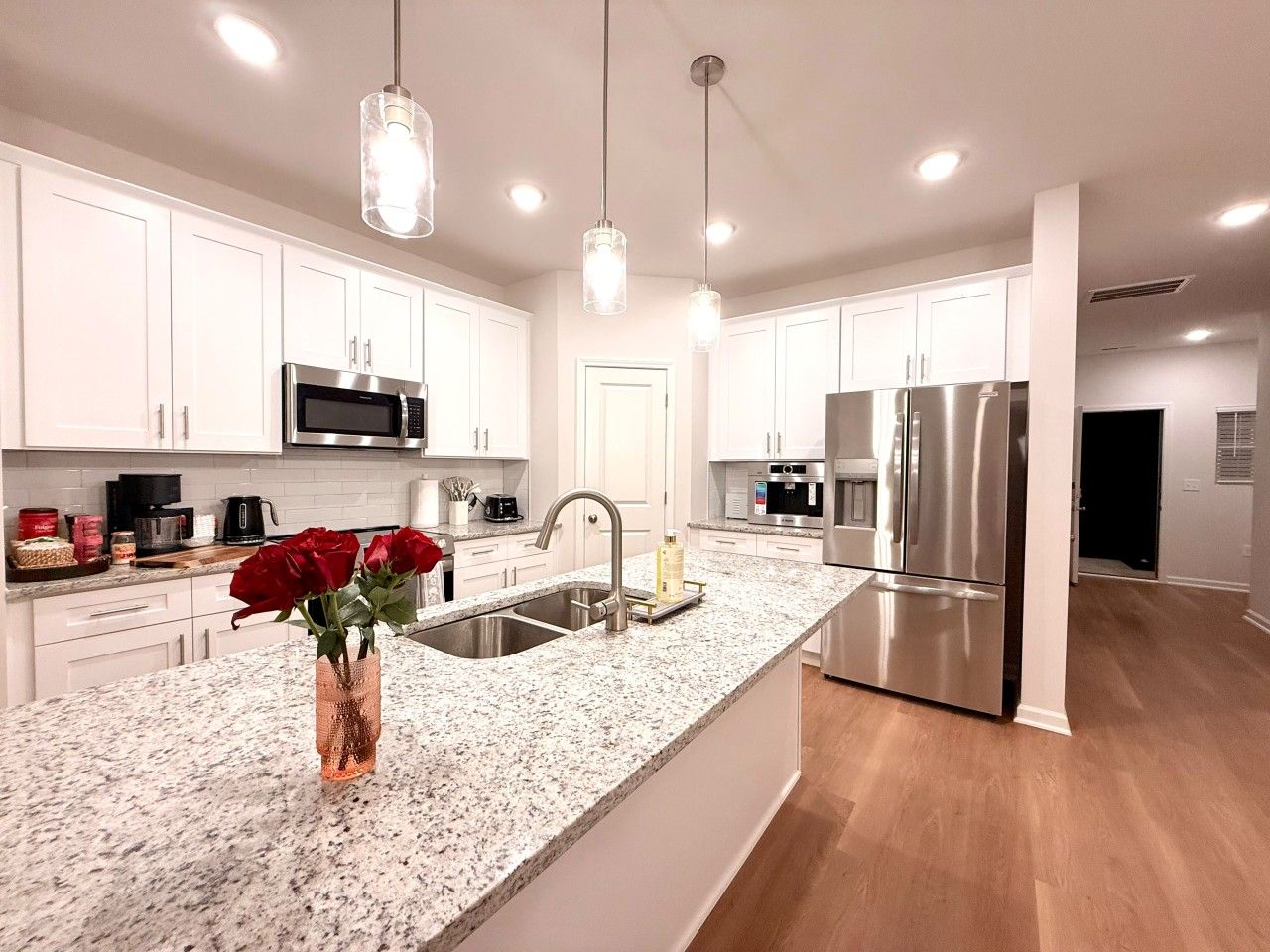 A modern kitchen with white cabinets, stainless steel appliances, and a granite countertop.