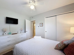 A bedroom with a bed, a dresser, a television, a ceiling fan, and a door. - Spacious 4-bedroom house in superb Largo with cool vibes (Largo)