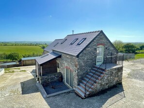 A stone building with a sloped roof, a small porch, and a staircase leading to a door. - The Cart Barn at Cadwgan Farm (Whitland)