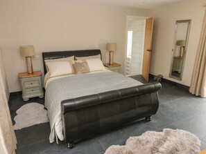 A bedroom with a bed, nightstands, a mirror, and a door. - The Cart Barn at Cadwgan Farm (Whitland)