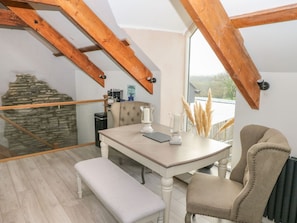 An attic room with a table, bench, and chairs. - The Cart Barn at Cadwgan Farm (Whitland)