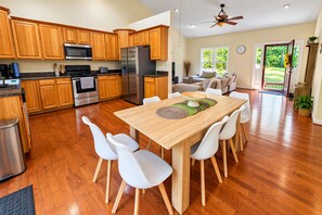 Eine moderne Küche mit Holzschränken, Edelstahlgeräten und einem Essbereich mit einem Holztisch und weißen Stühlen.