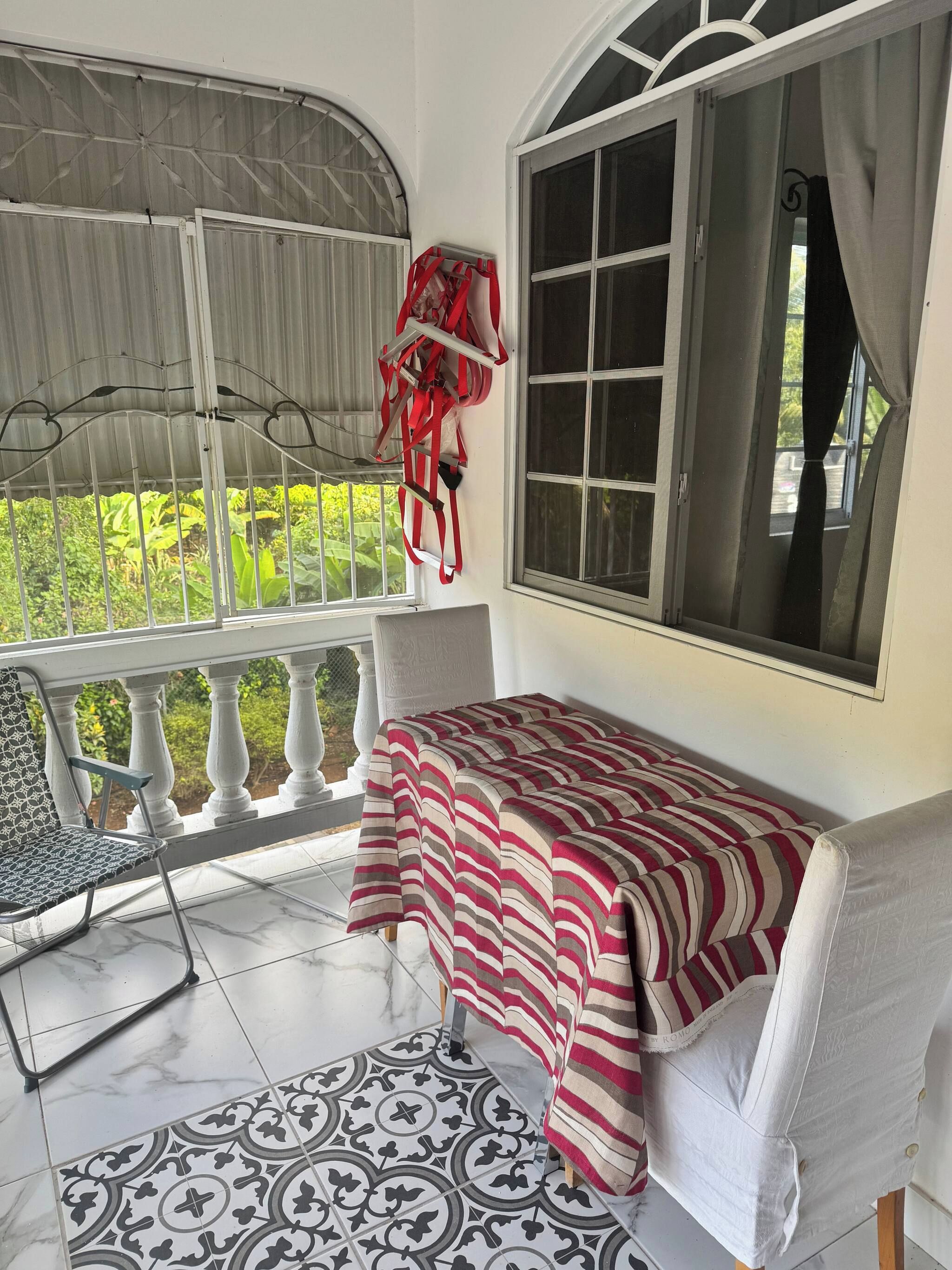 A room with a bed, a chair, a window, and a view of greenery.