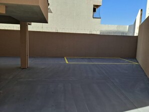 Eine Dachterrasse mit blauer Fläche, einer gelben Markierung und einem Stacheldrahtzaun.