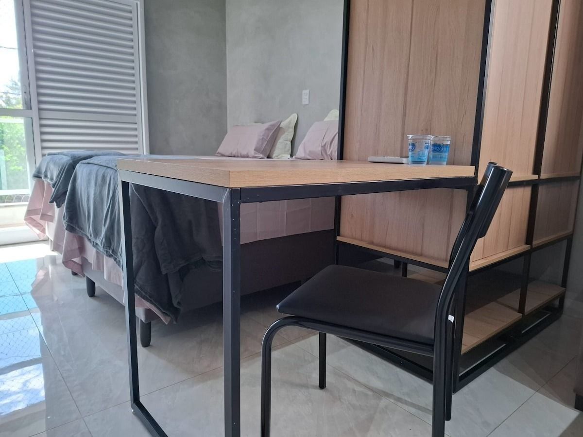 A room with a bed, a desk, a chair, and a wardrobe.