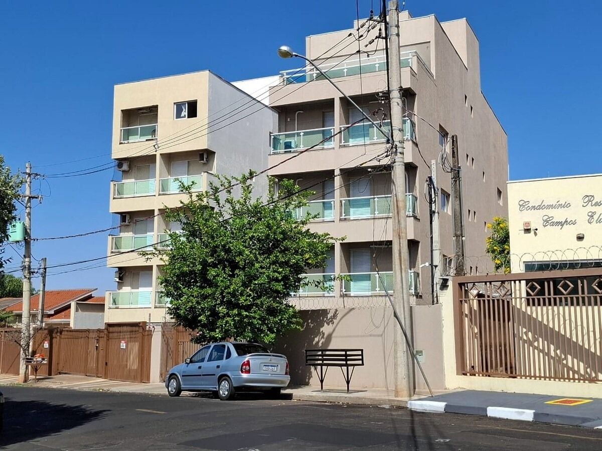 A multi-story residential building with balconies, a gated entrance, and a parked car.