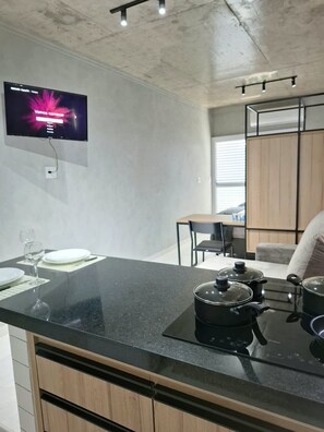 A modern kitchen with a black countertop, a stove, and a television mounted on the wall. - Edifício 1139 (São José do Rio Preto)