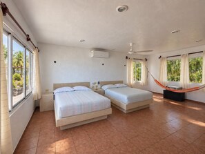 Ein Hotelzimmer mit zwei Betten, einem Deckenventilator und einer Hängematte.