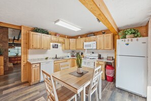 Eine Küche mit Holzausstattung, einem weißen Kühlschrank und einem Esstisch mit Stühlen.