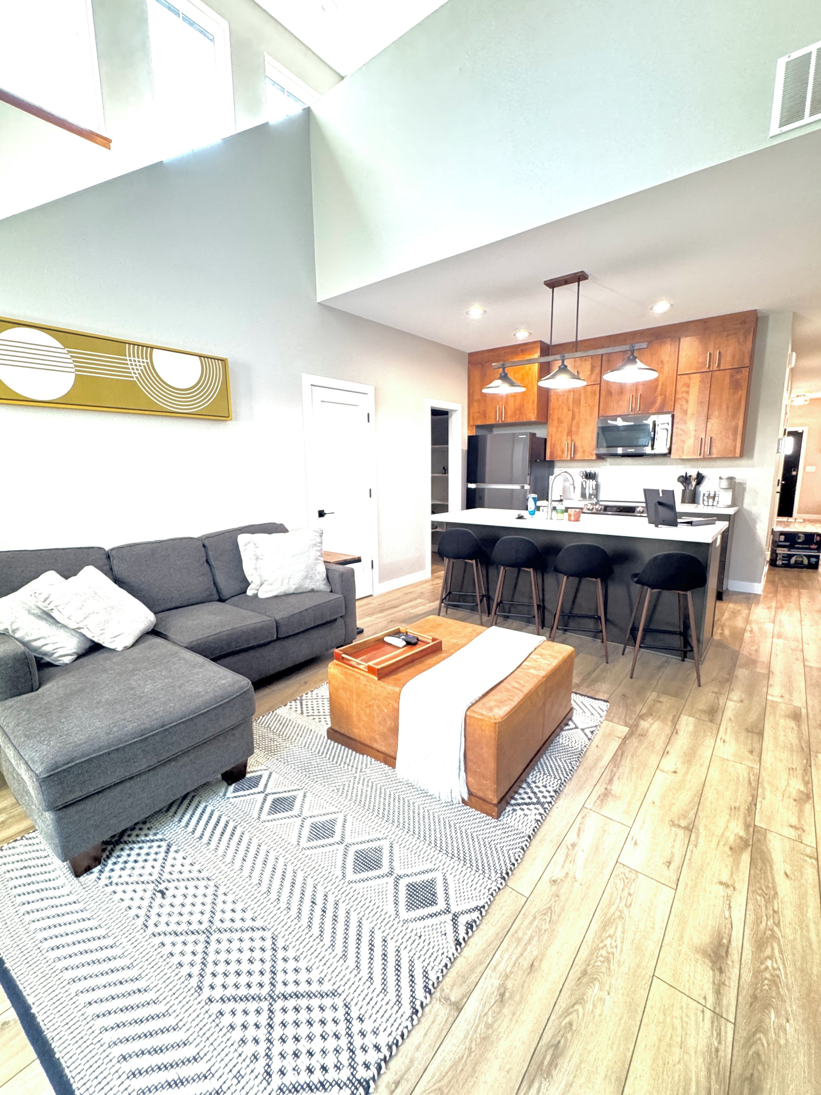 Ein modernes Wohnzimmer mit einem grauen Sofa, einem Couchtisch und einem gemusterten Teppich.