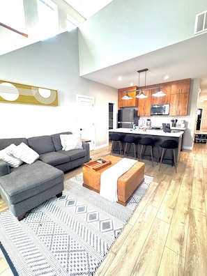 A modern living room with a grey sofa, a coffee table, and a patterned rug. - New Cozy 2-Bedroom Townhome in Central Bismarck (Bismarck)