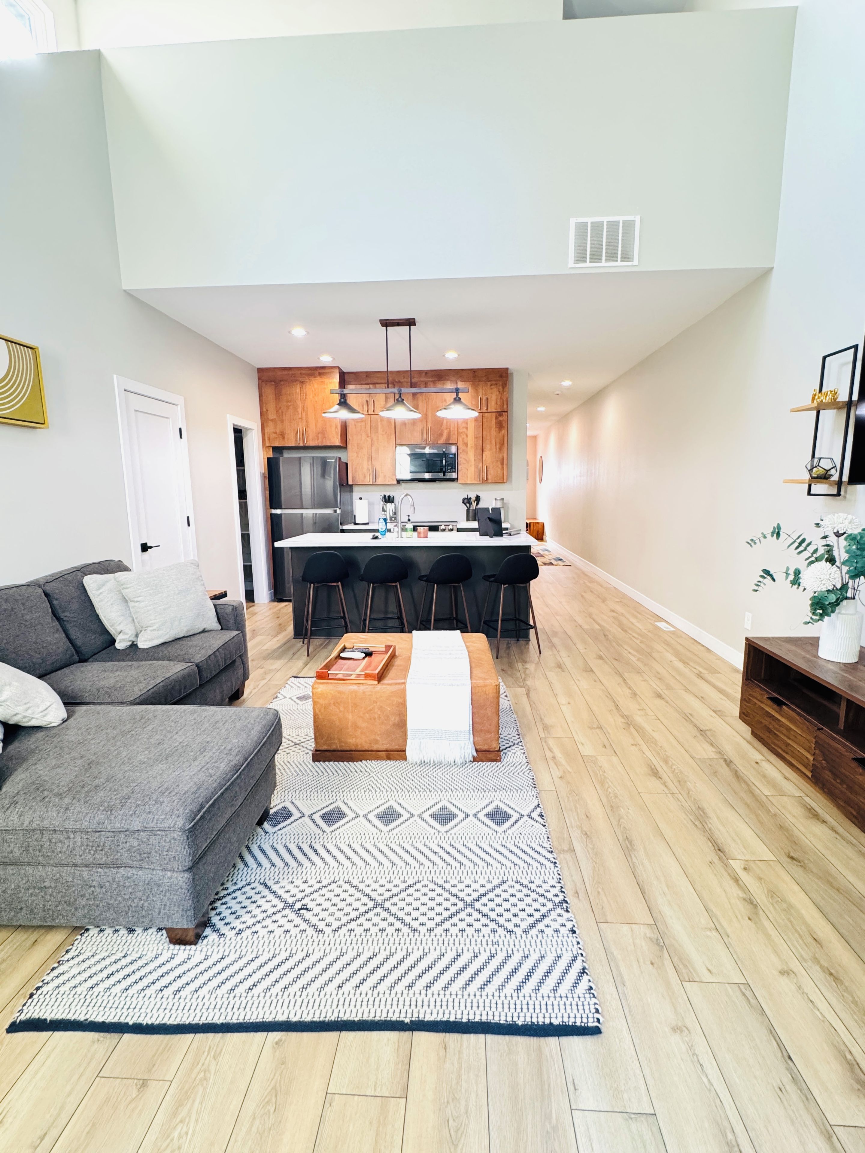 A modern living room with a sofa, ottoman, and a patterned rug.