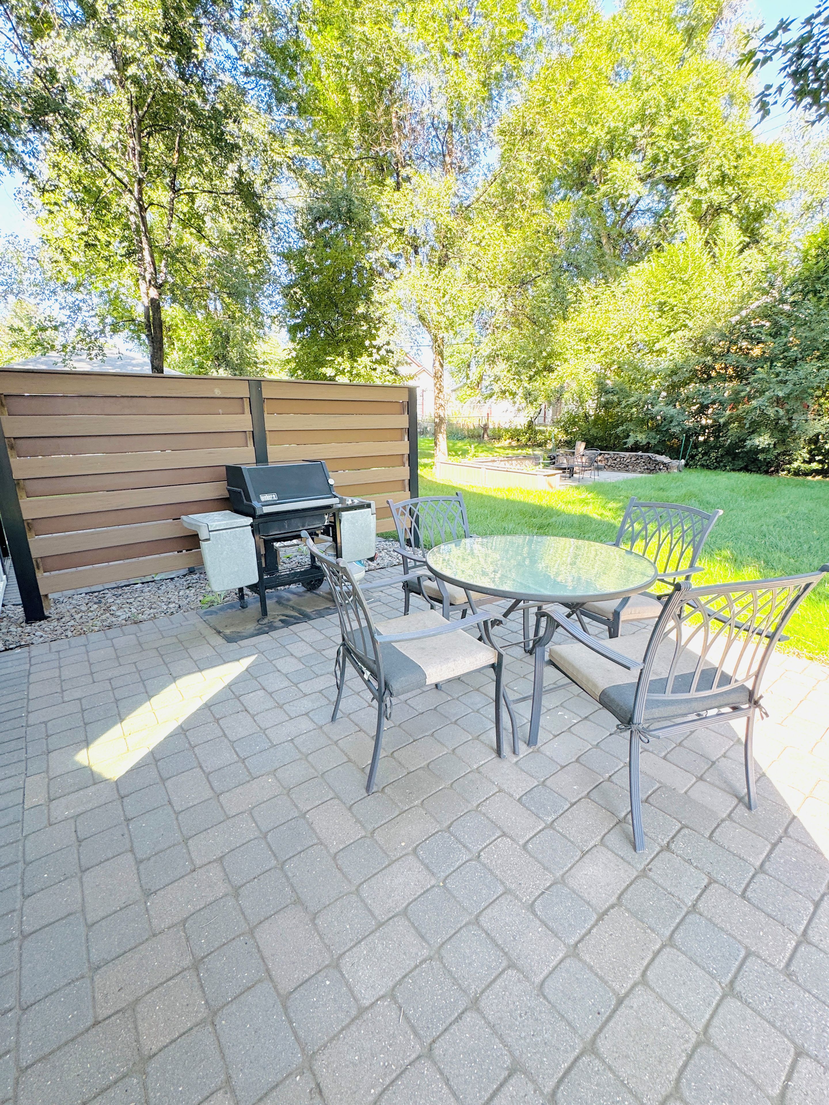 An outdoor patio with a grill, table, and chairs.