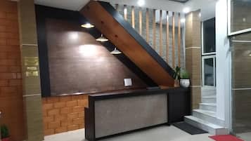 Una recepción de diseño moderno, una escalera con barandilla de madera y una planta en maceta.