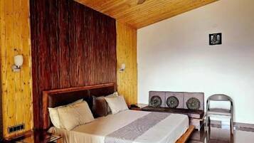 Un dormitorio con techo de madera, una cama, una mesita de noche, una silla y un ventilador de techo.