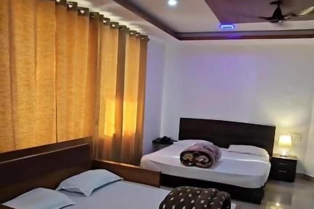 A hotel room with a large bed, a smaller bed, a nightstand, and a ceiling fan.