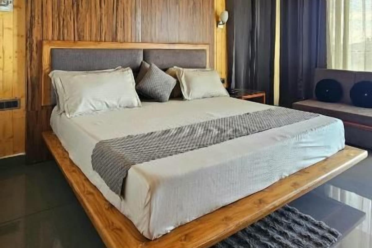 A bedroom with a wooden ceiling, a bed with a headboard, and a ceiling fan.
