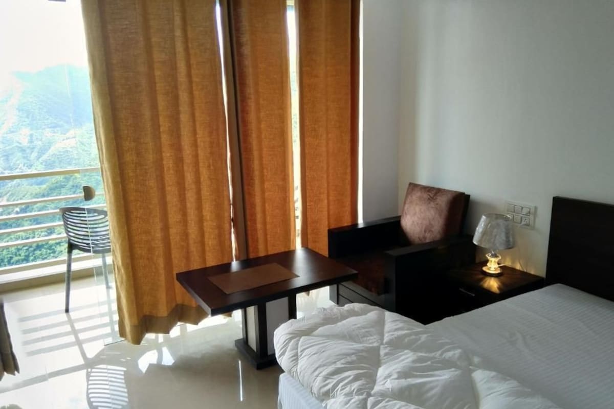 A hotel room with a bed, a desk, a chair, and a view of the outdoors.