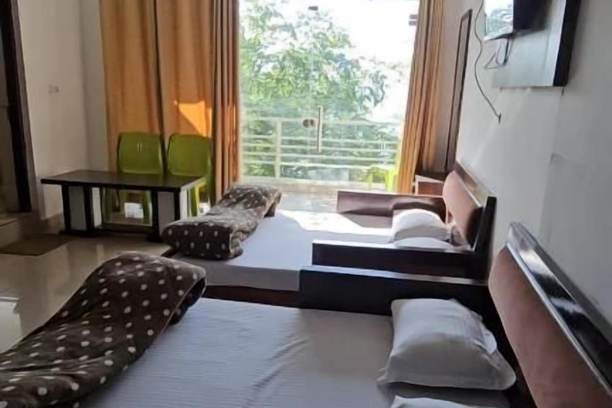 A hotel room with a bed, a sofa, a TV, and a balcony with curtains.