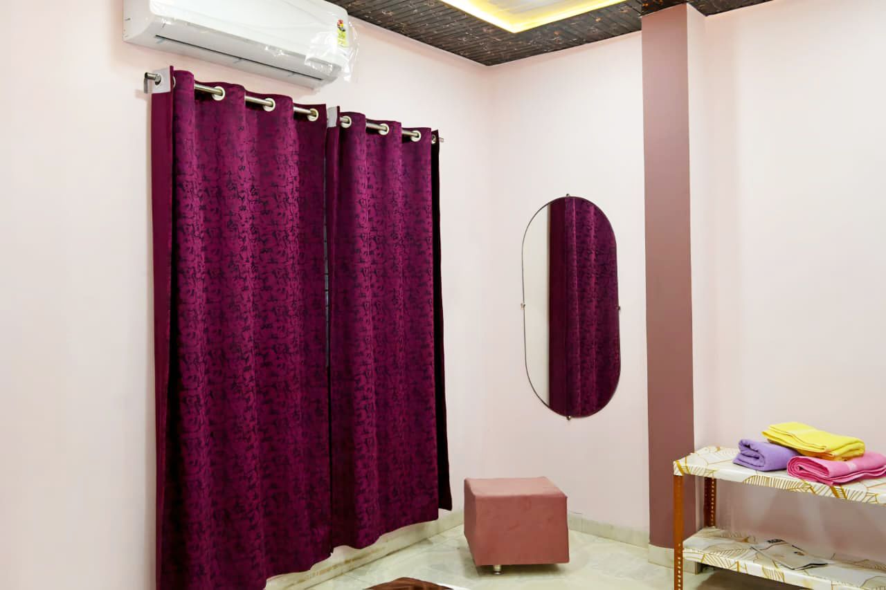 A bathroom with a shower curtain, a mirror, a small stool, and a shelf with folded towels.