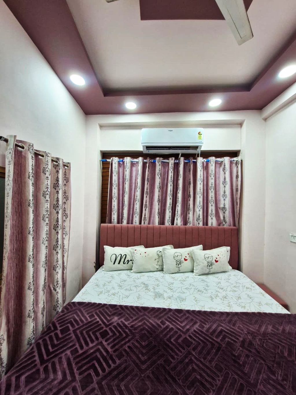 Ein Schlafzimmer mit einem Bett, Vorhängen, einer Klimaanlage und einem Deckenventilator.