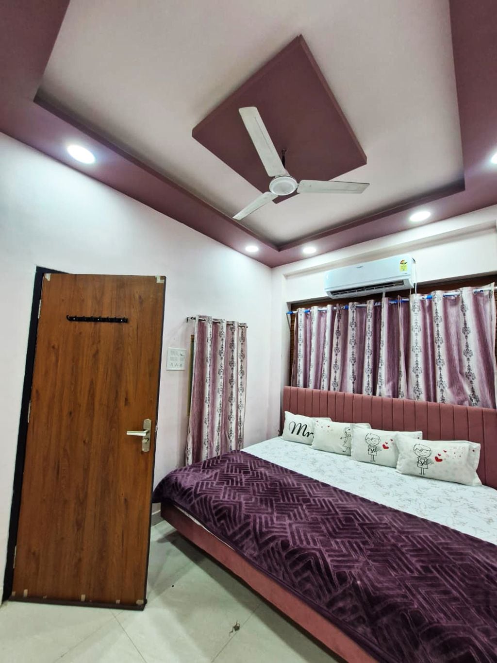 Un dormitorio con cama, ventilador de techo, puerta y cortinas.