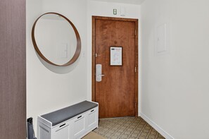 A hallway with a wooden door, a white bench, and a wall-mounted mirror. - Johannsen 359 (Mont-Tremblant)