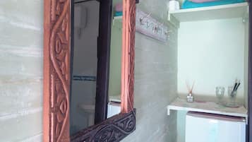 A room with a wooden-framed mirror, a white refrigerator, and a small sink area.