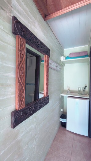 A room with a wooden-framed mirror, a white refrigerator, and a small sink area. - Pousada Canto da Galheta (Paranaguá)