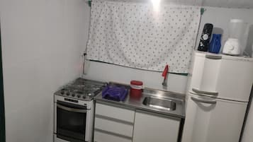 A compact kitchen with a gas stove, oven, sink, and a refrigerator.