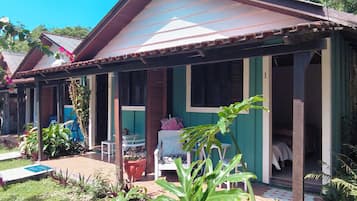 A house with a porch, a garden with various plants, and a clear blue sky.