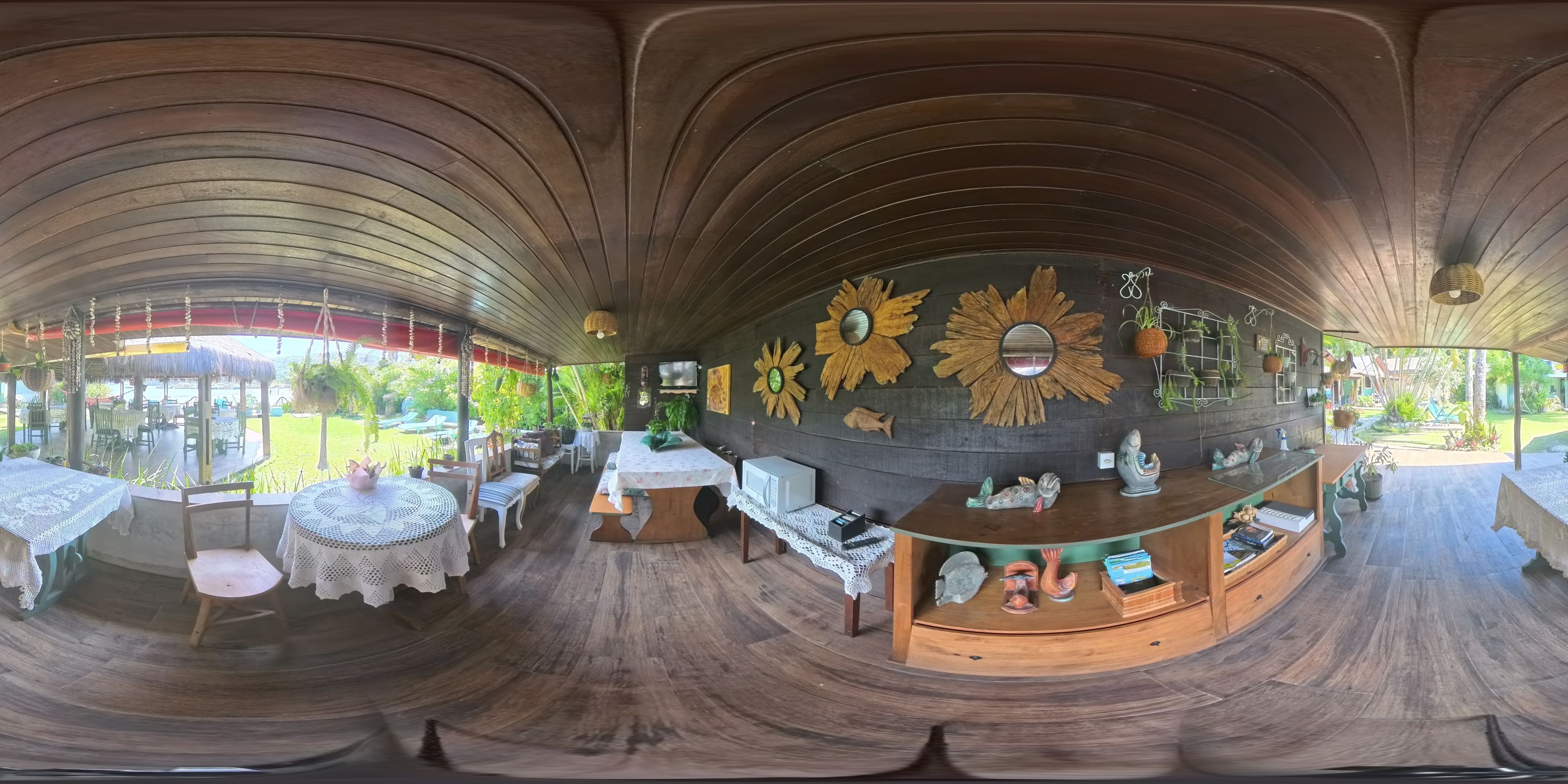 Un vaste espace intérieur doté d’un plancher en bois, d’un coin salon central avec des tables et des chaises, et d’un mur décoré de tournesols et de miroirs.