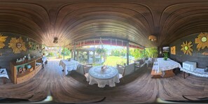 A room with a curved ceiling, wooden flooring, and tables with lace tablecloths.