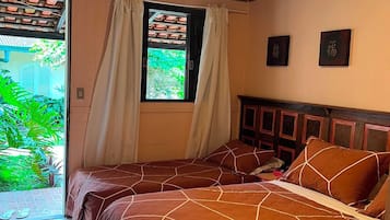 A room with two beds, a window with curtains, and a ceiling light.