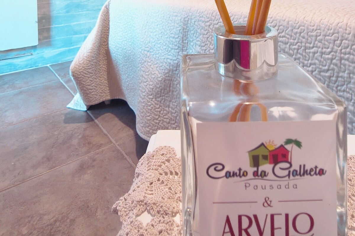 Una ampolla de perfum Arveo en un recipient de vidre transparent amb etiqueta, col·locada sobre una superfície amb textura.