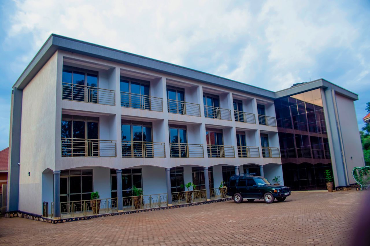 A multi-story building with a flat roof, large windows, and a paved entrance area.