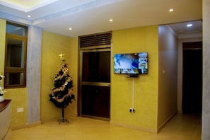 A room with a television mounted on the wall, a Christmas tree, and a sliding door. - Spark Africa Hotel Jinja (Jinja)