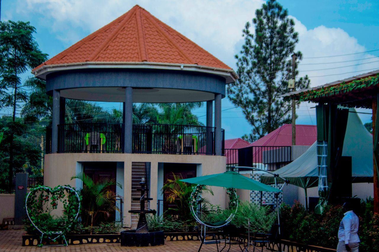 A gazebo with a tiled roof, surrounded by greenery and outdoor furniture.